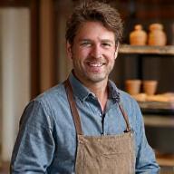 Portrait of Artisan Leo Stone, a ceramic therapy specialist, demonstrating pottery techniques with focused hands.