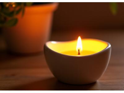 Small, smooth ceramic bedside oil warmer gently warming a fragrant essential oil, creating a soft glow and releasing soothing scents for immediate relaxation.